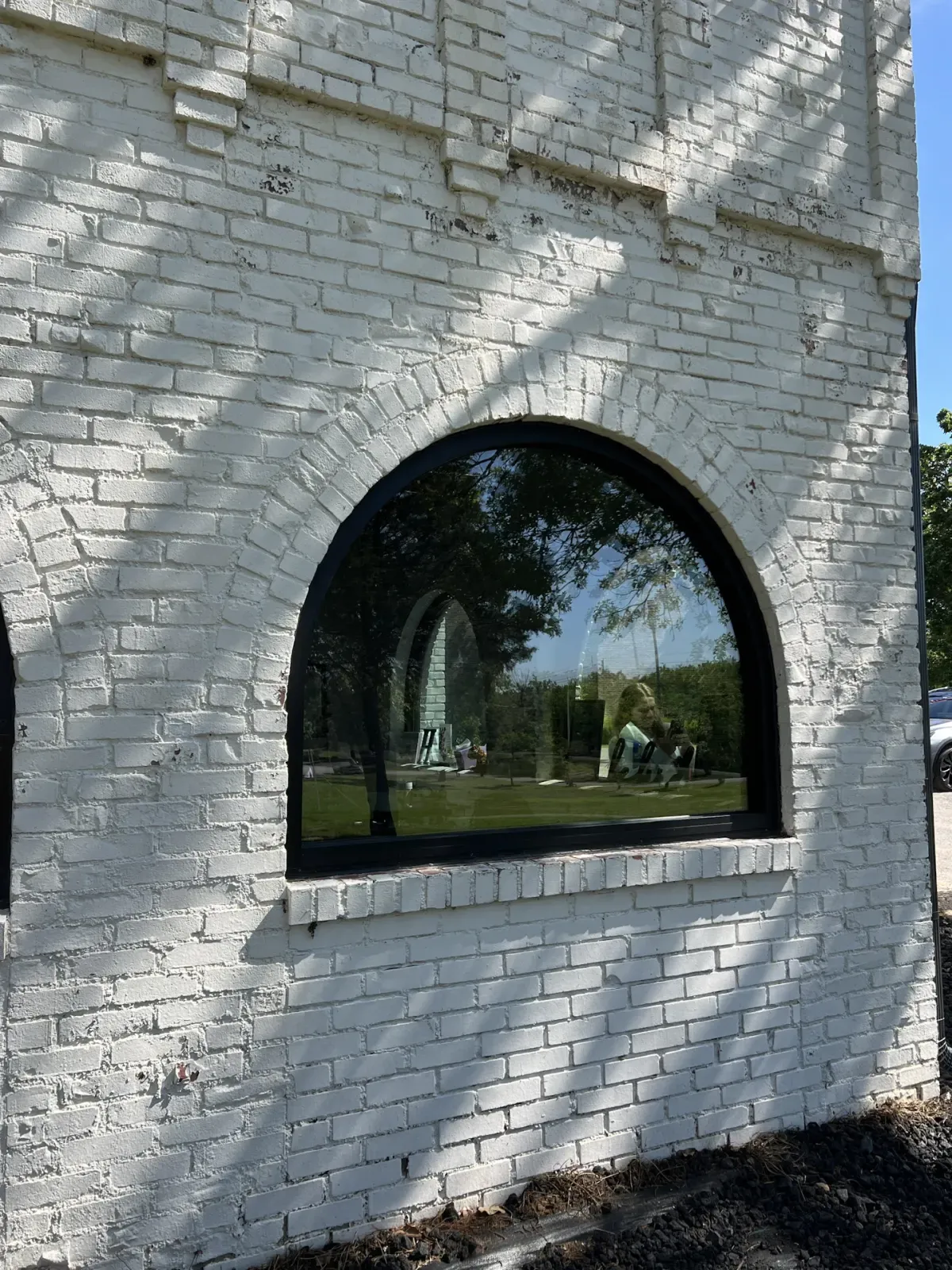 Close-up of an arched black window in a painted brick opening