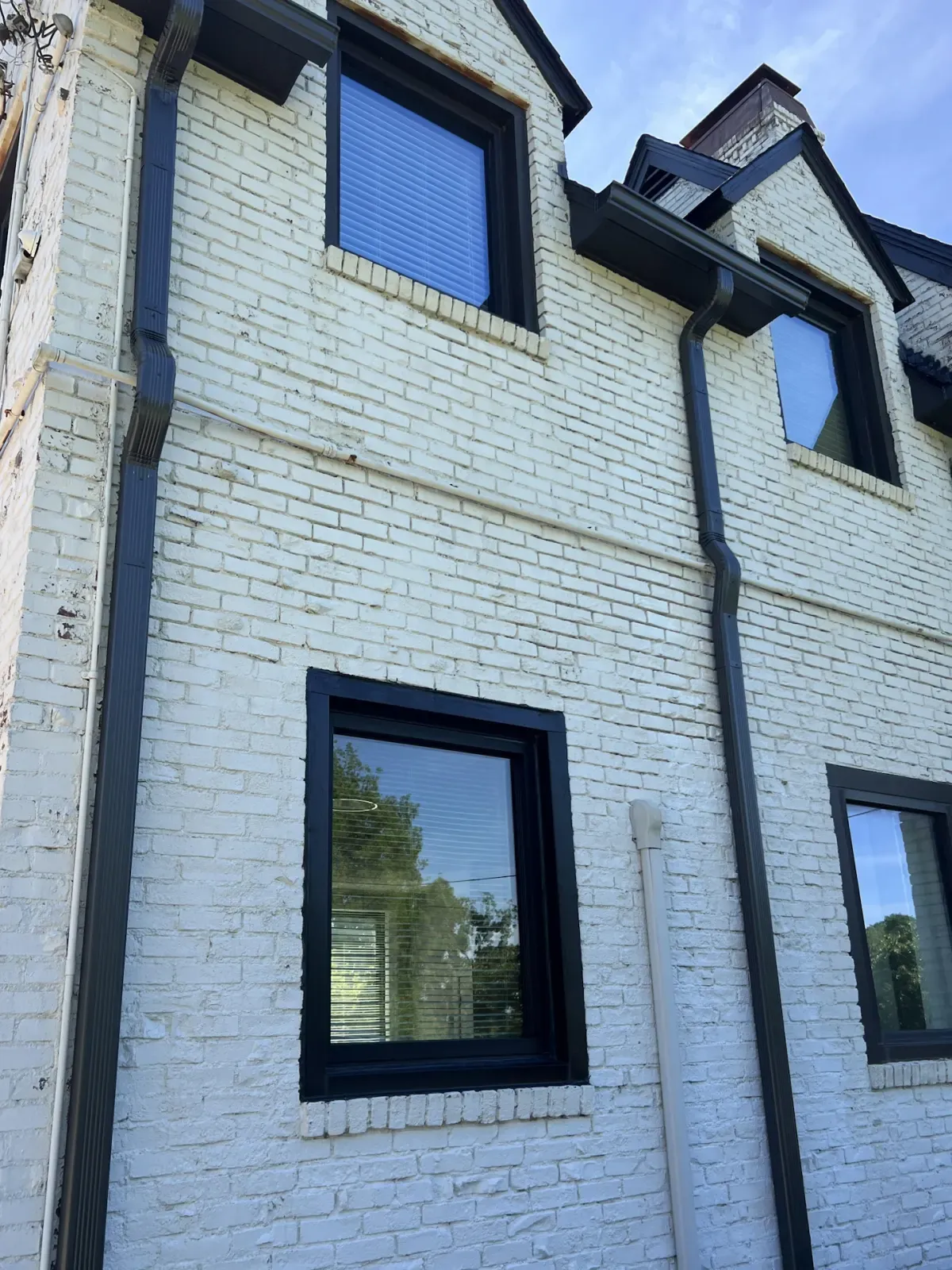 Black-frame windows on the side of a two-story white brick home