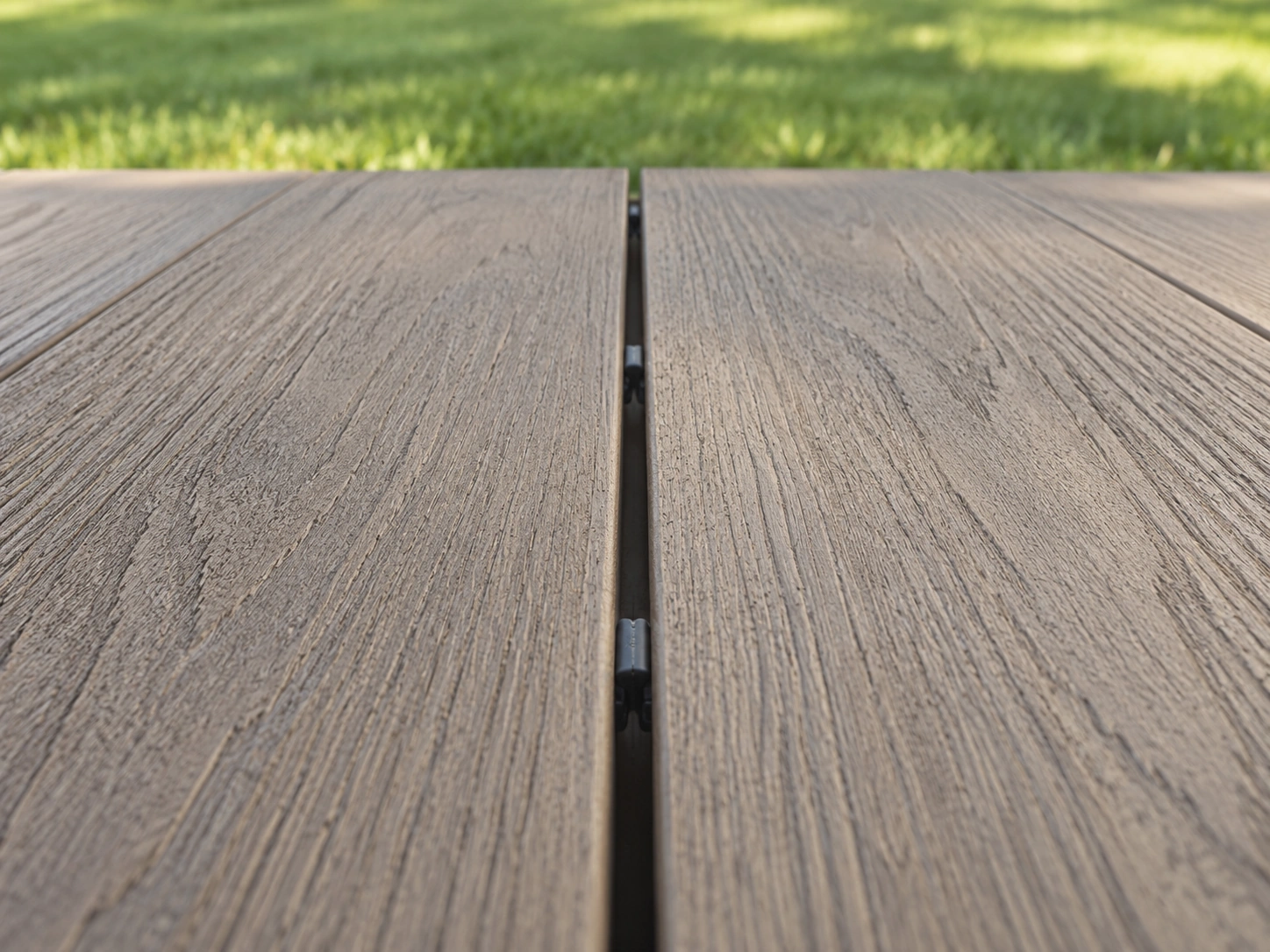 Close-up of two capped decking boards showing the grain and a hidden fastener gap