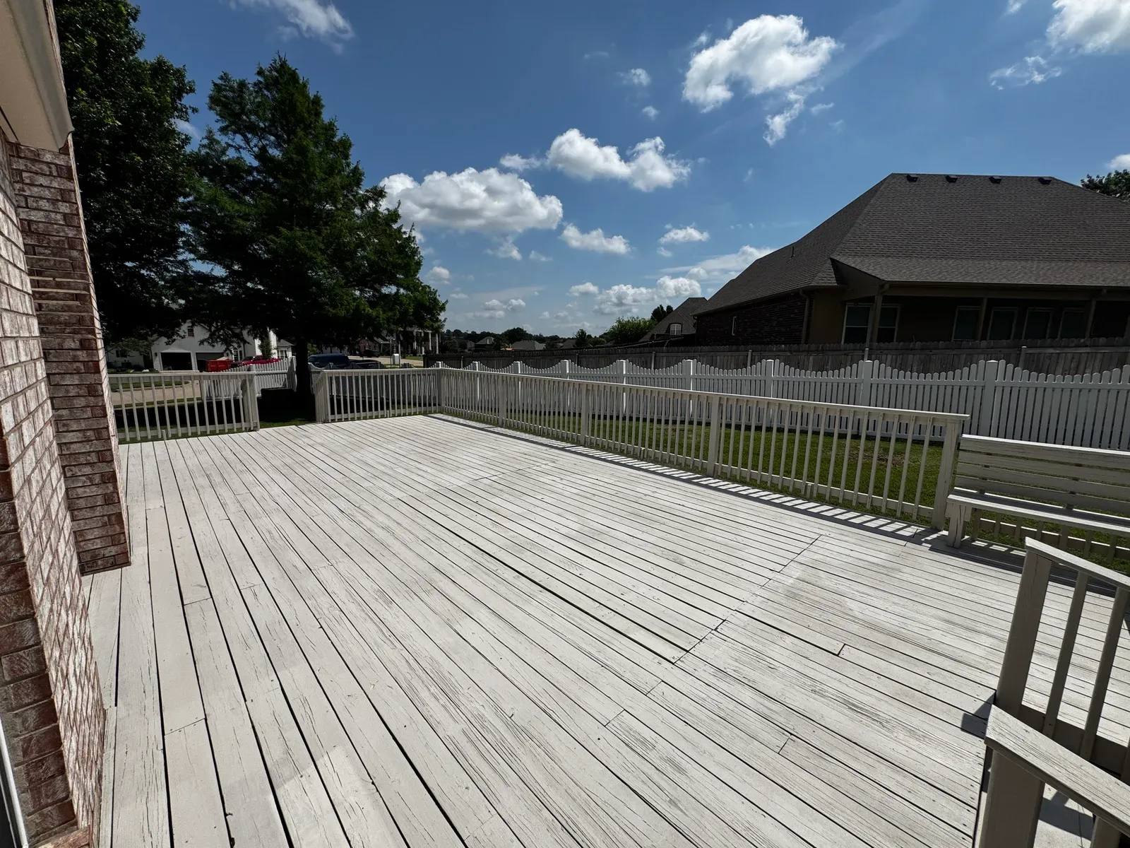 Wide view of a finished deck with white railing and built-in bench