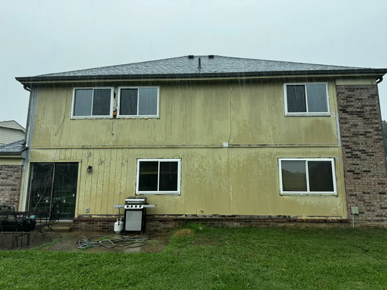 Before: faded, peeling original siding and old windows on the back of a two-story home